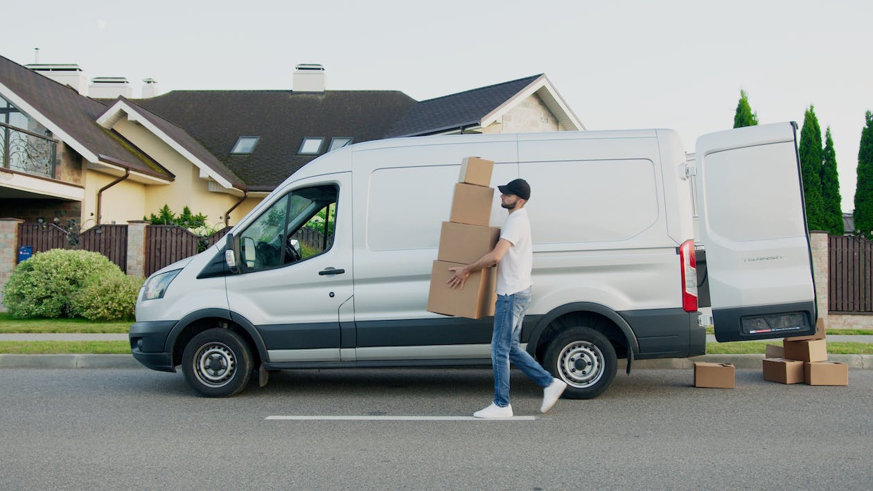 Man carrying boxes from white truck