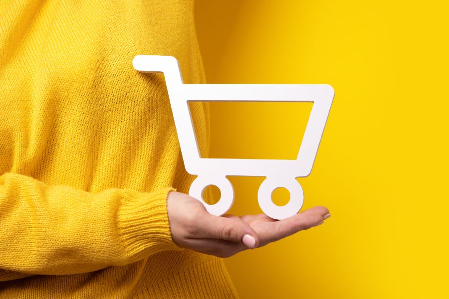 shopping cart on hand over yellow background