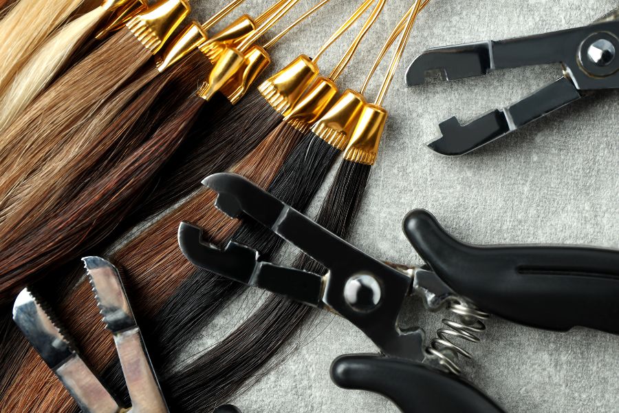 Hair extensions and tools on grey background